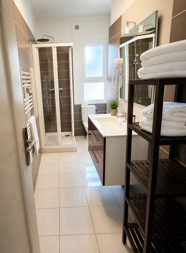 Salle de bain moderne de la chambre double terrasse vue mer à l’Hôtel Le Kallisté à Hyères avec douche, vasque et serviettes